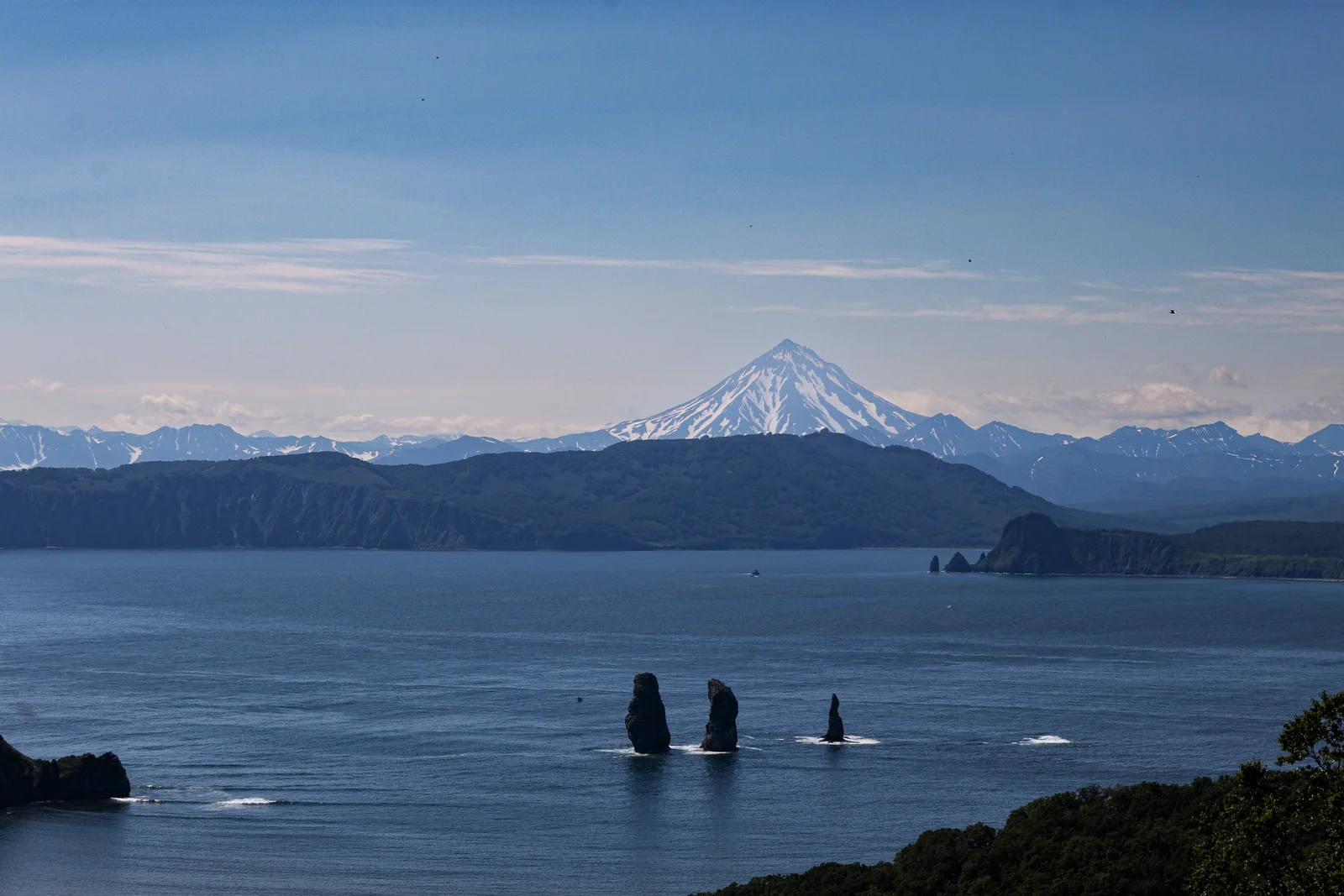 Ocean, coastal cliffs and a snow-covered volcano on the horizon